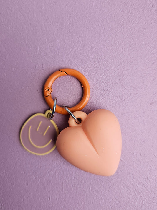 Hartje sleutelhanger met een vrolijke smiley in de kleur perzik