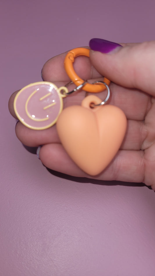 Hartje sleutelhanger met een vrolijke smiley in de kleur perzik